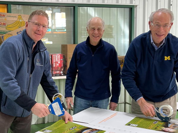 Three men smiling while working on a display.