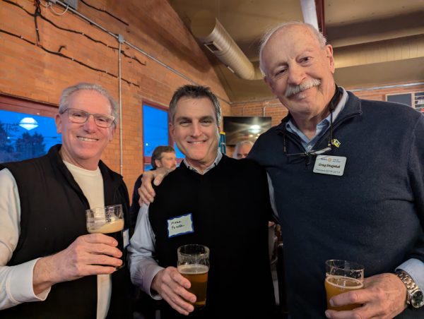 Three men smiling at the camera, with beers in their hands.