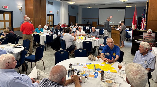 Members and guests seated at tables at a Rotary Club meeting.