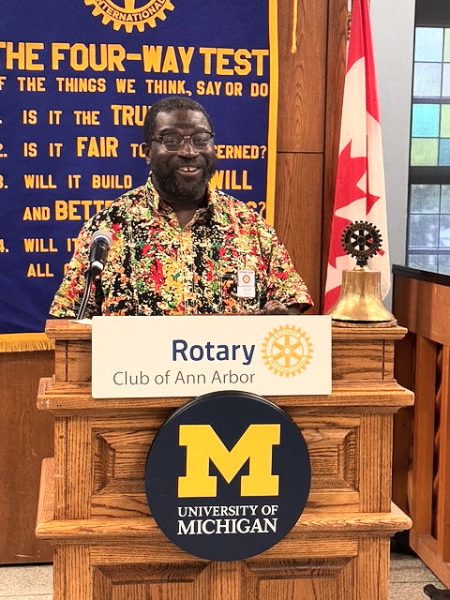 Black man with a colorful shirt at the podium.