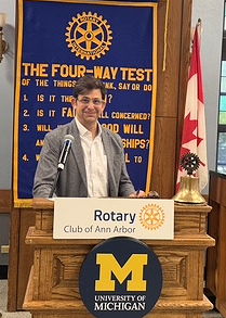 White man at podium wearing a sports jacket.