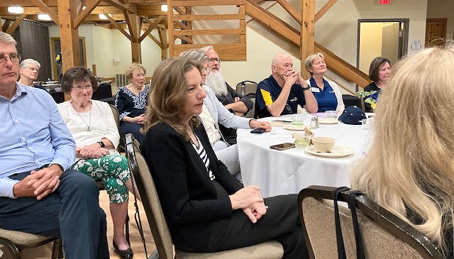 People seated at tables listening to a speaker.