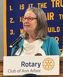 Woman at podium, speaking into a microphone.