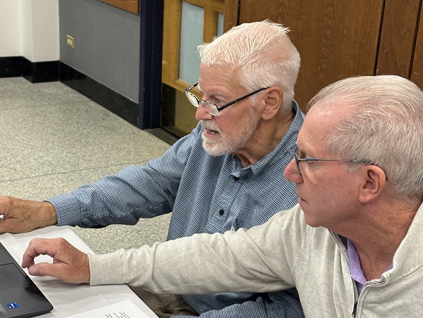 Two men staring at a computer.