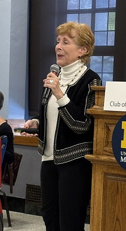 Woman standing, speaking into microphone.