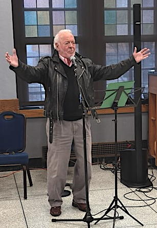 Man wearing a leather jacket, with arms spread.