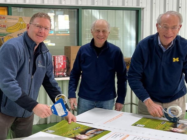 Three men preparing posters.