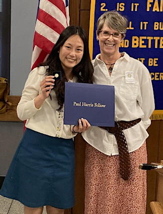Two women, one holding a pin and a certificate of achievment.